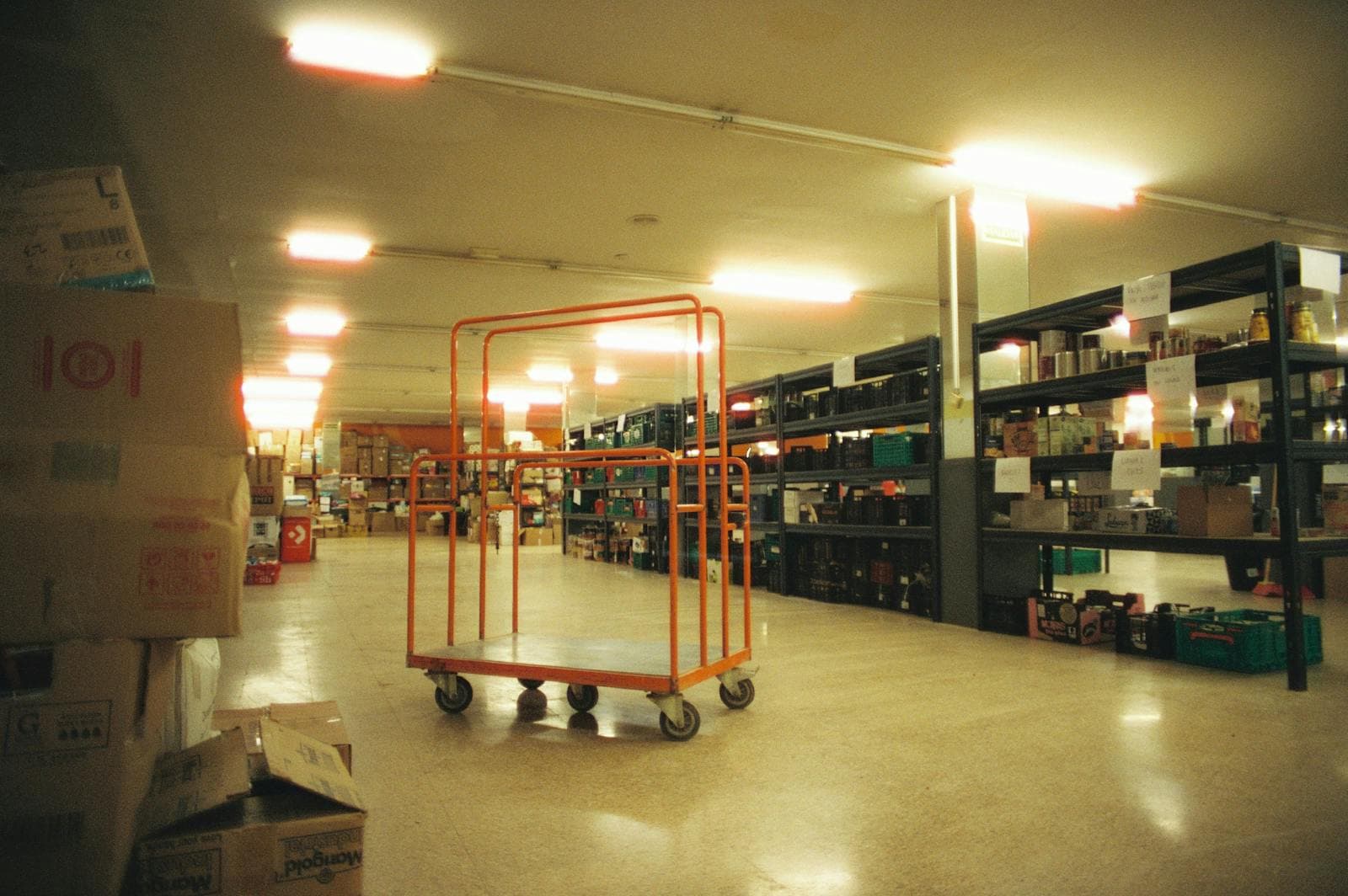 Spacious warehouse interior with metal shelving racks and a picking cart.
