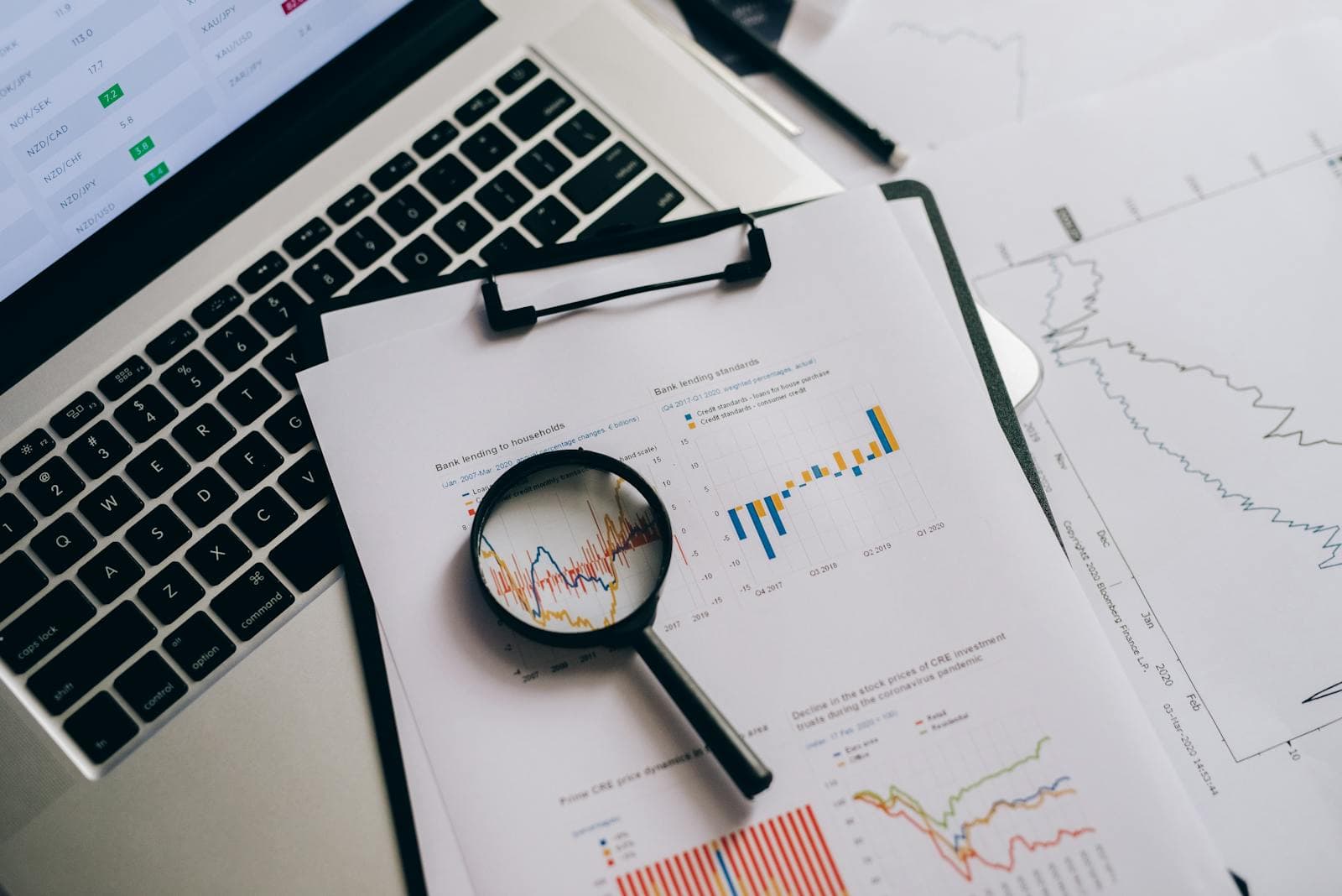 Magnifying glass resting on a printed page of statistical data and charts.